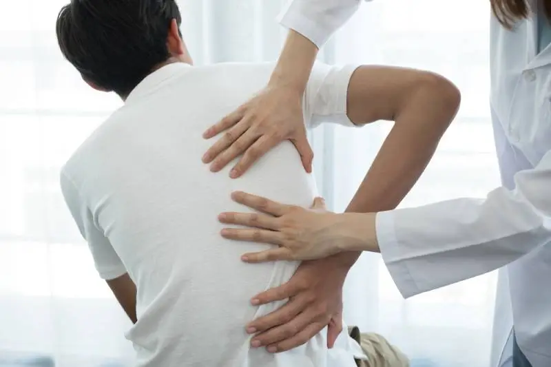 Doctor evaluating lower back pain and musculoskeletal conditions at Magnet Health NY, 907 E Tremont Ave, Bronx, NY 10460