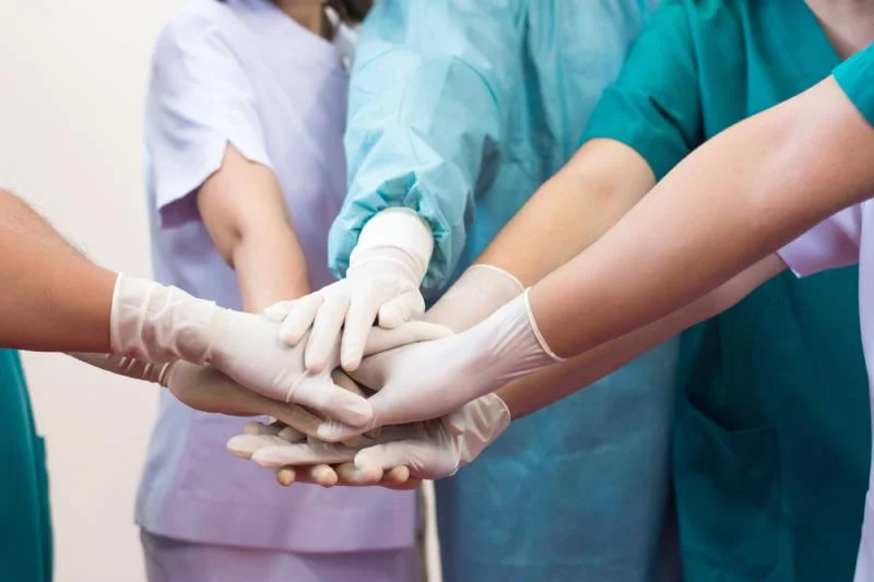 Multidisciplinary healthcare team joining hands at Magnet Health NY clinics in the Bronx — delivering compassionate, community-centered care at 907 E Tremont Ave and 741 E 233rd St.